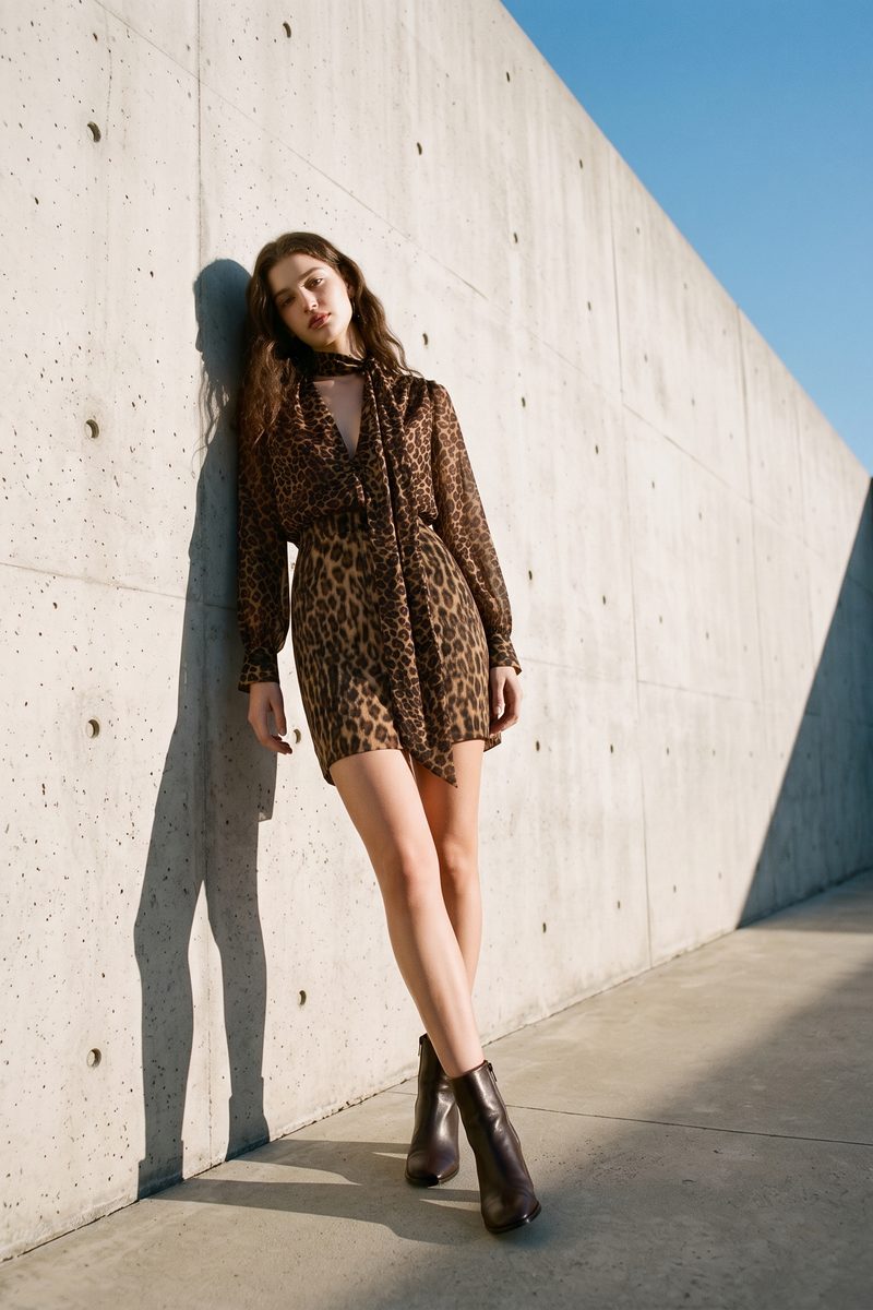 AI on-model editorial photo, leopard print mini dress against a sunlit board-formed concrete wall