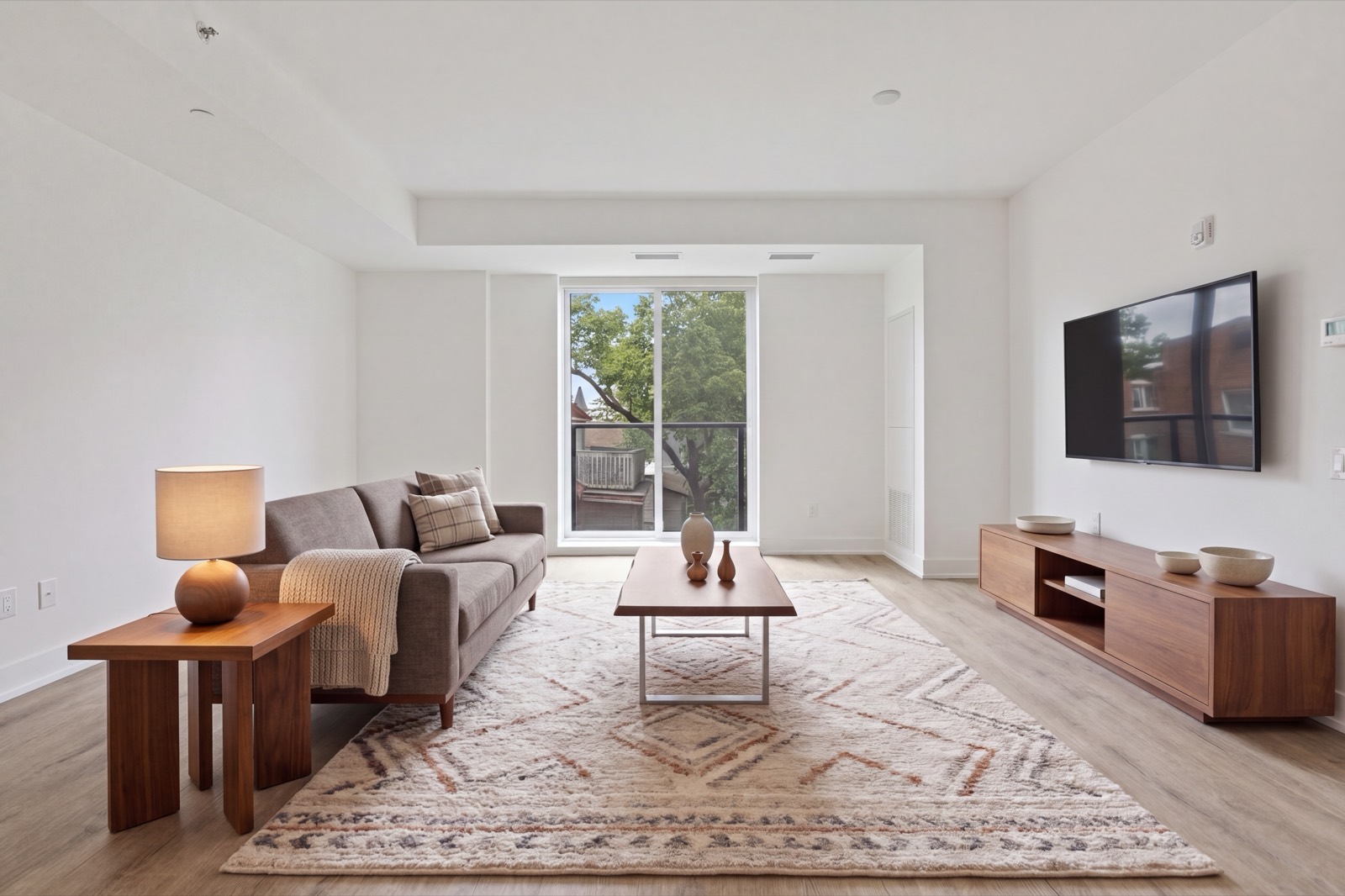 The same living room and the same furniture seen from the opposite corner, sofa, rug, lamp and console unchanged